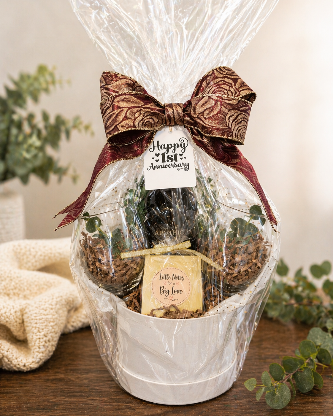A gift basket with a large bow, containing chocolates and a small card, decorated for a 1st anniversary celebration.