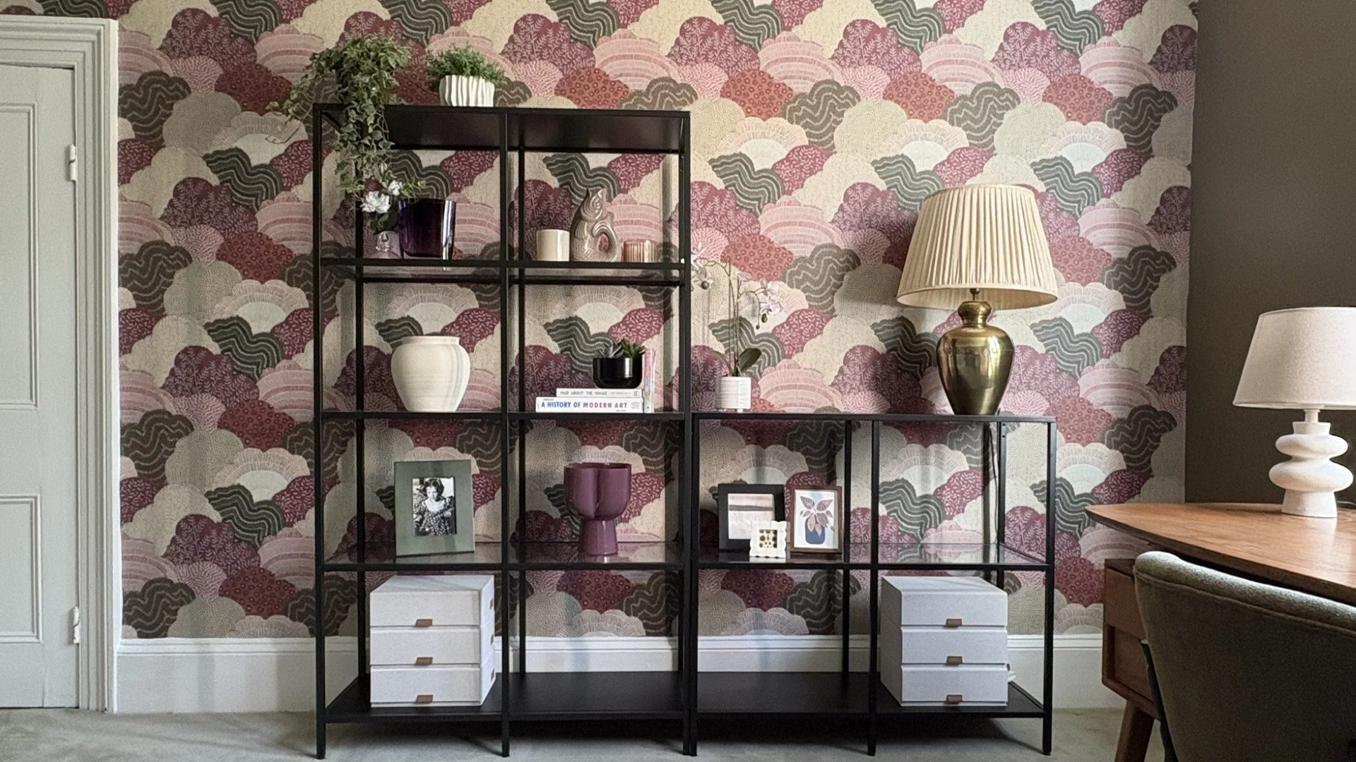 Home office geometric shelving against patterned wallpaper, combining functional storage with layered design
