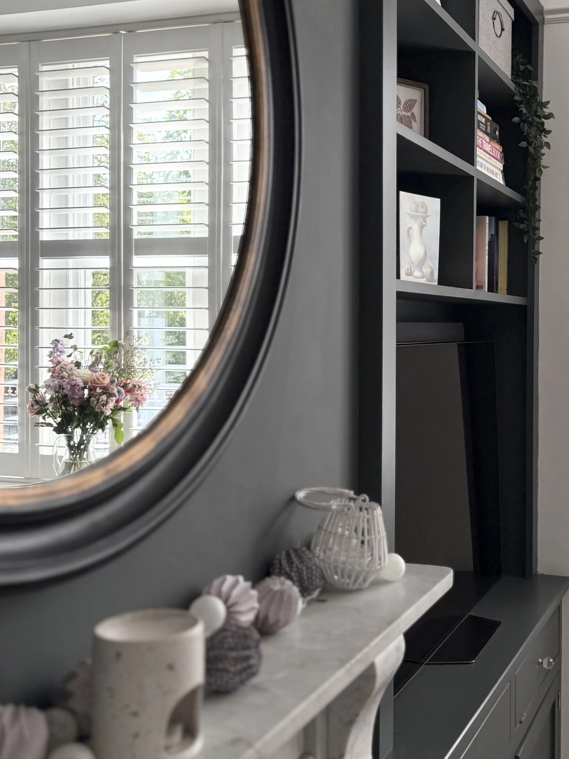Living room with large circular mirror, console table and built-in shelving