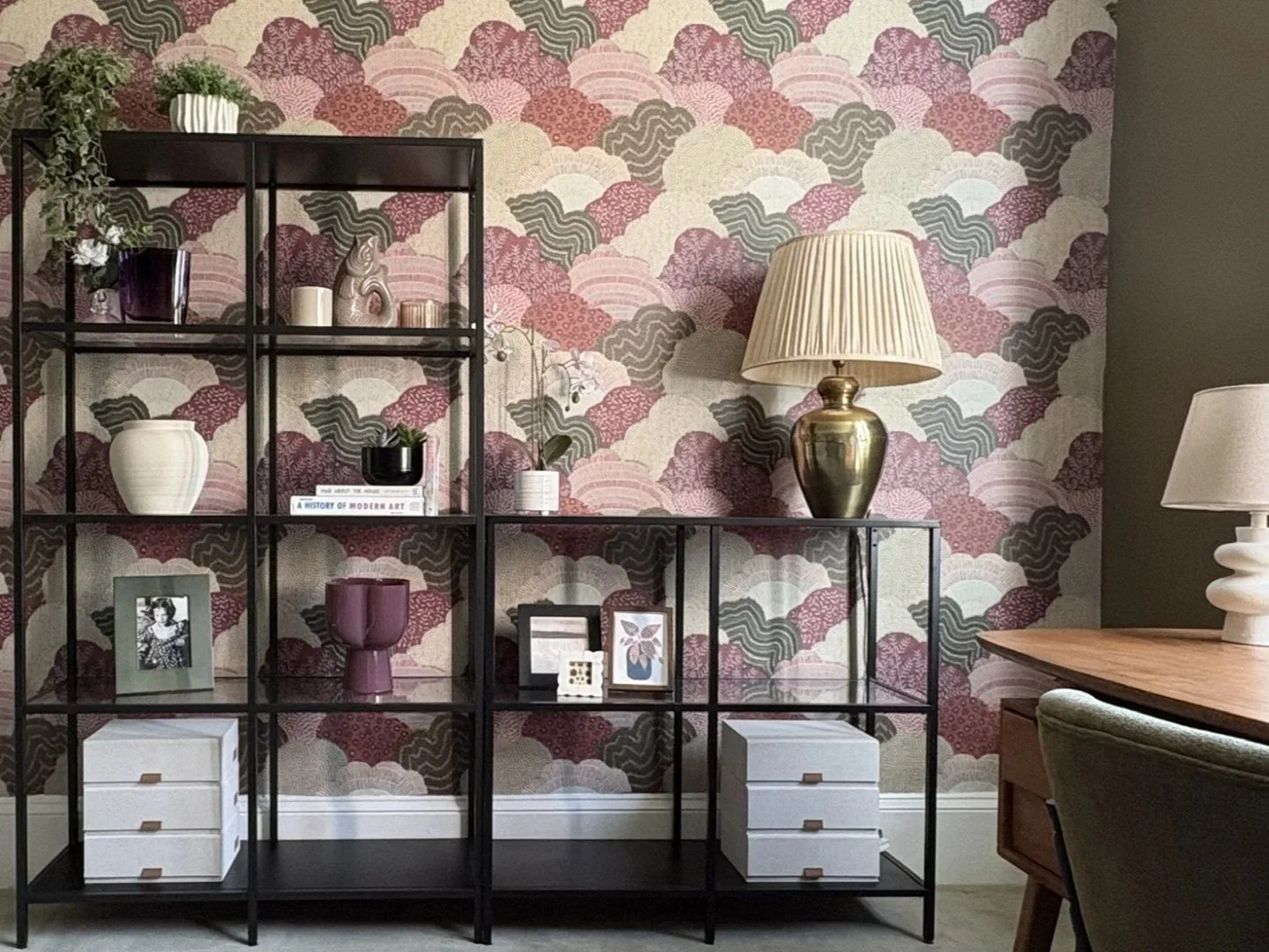 Home office with geometric shelving against patterned wallpaper, combining functional storage with layered design