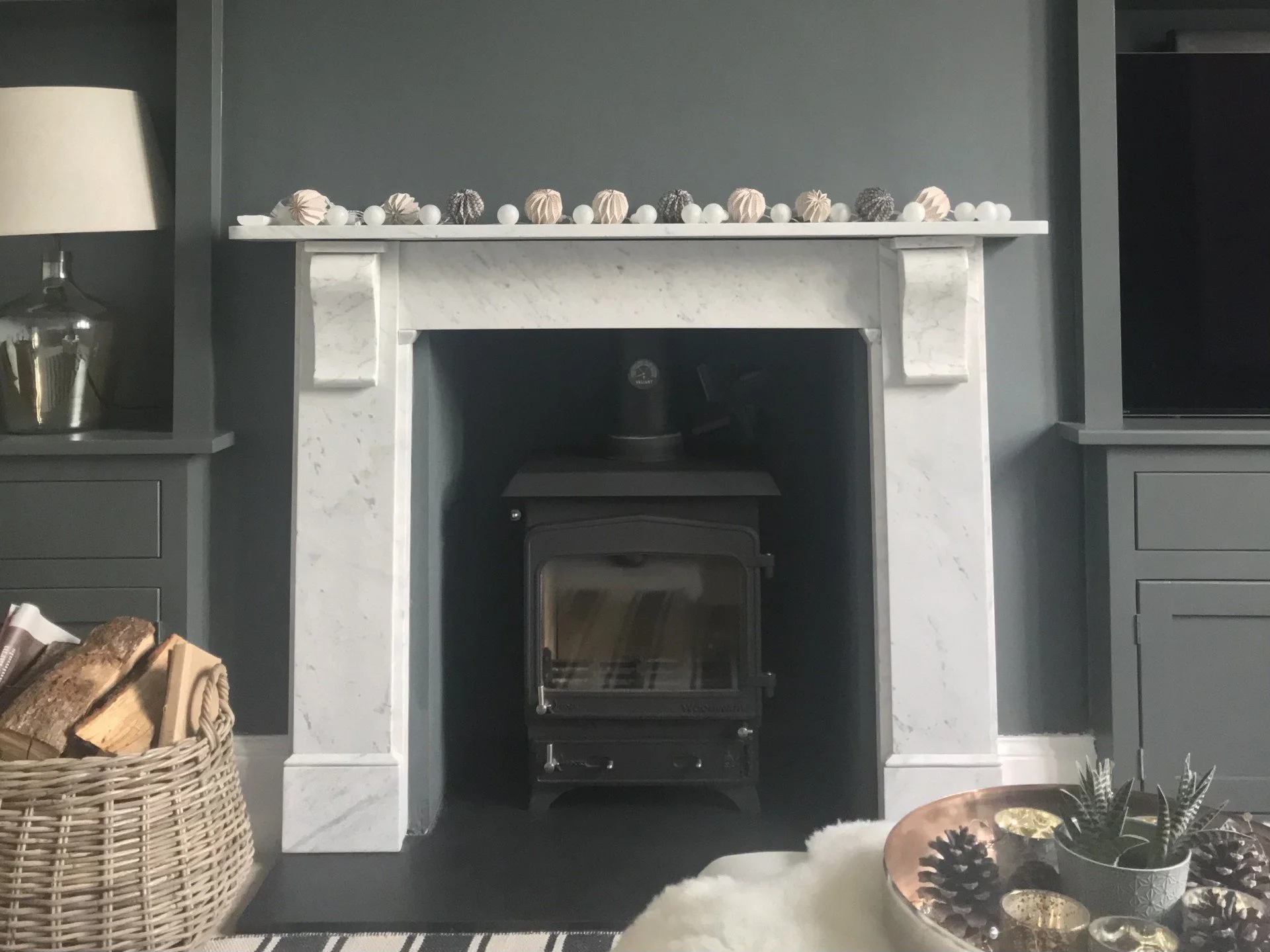 Refined living room with original marble fireplace, wood burner, dark grey cabinetry and layered styling