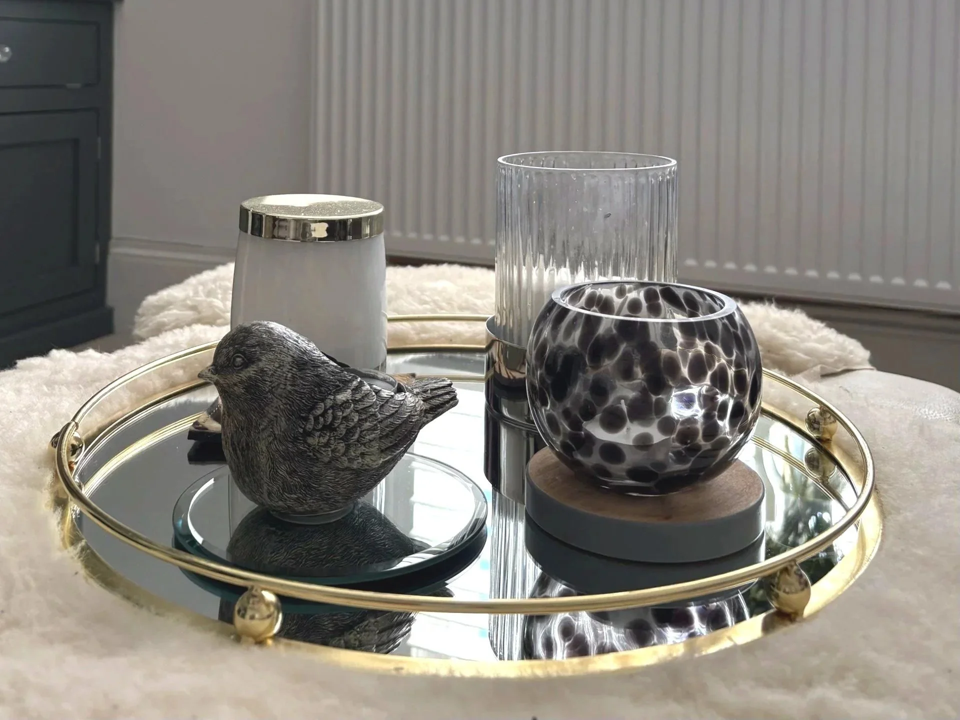 Layered sitting room vignette combining reflective glass, mirrored finishes, metallic accents, pattern and texture in a soft monochromatic palette