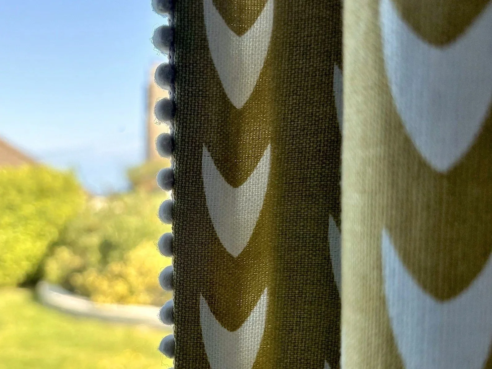 Contemporary patterned curtain with contrasting pom-pom trim, showing how considered detailing adds character to a room