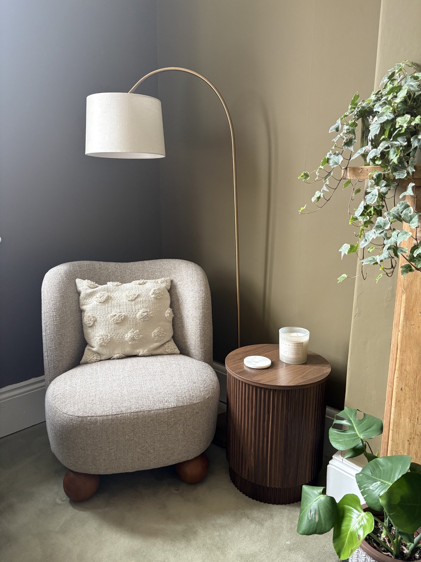 Layered corner vignette with upholstered accent chair, fluted side table and greenery