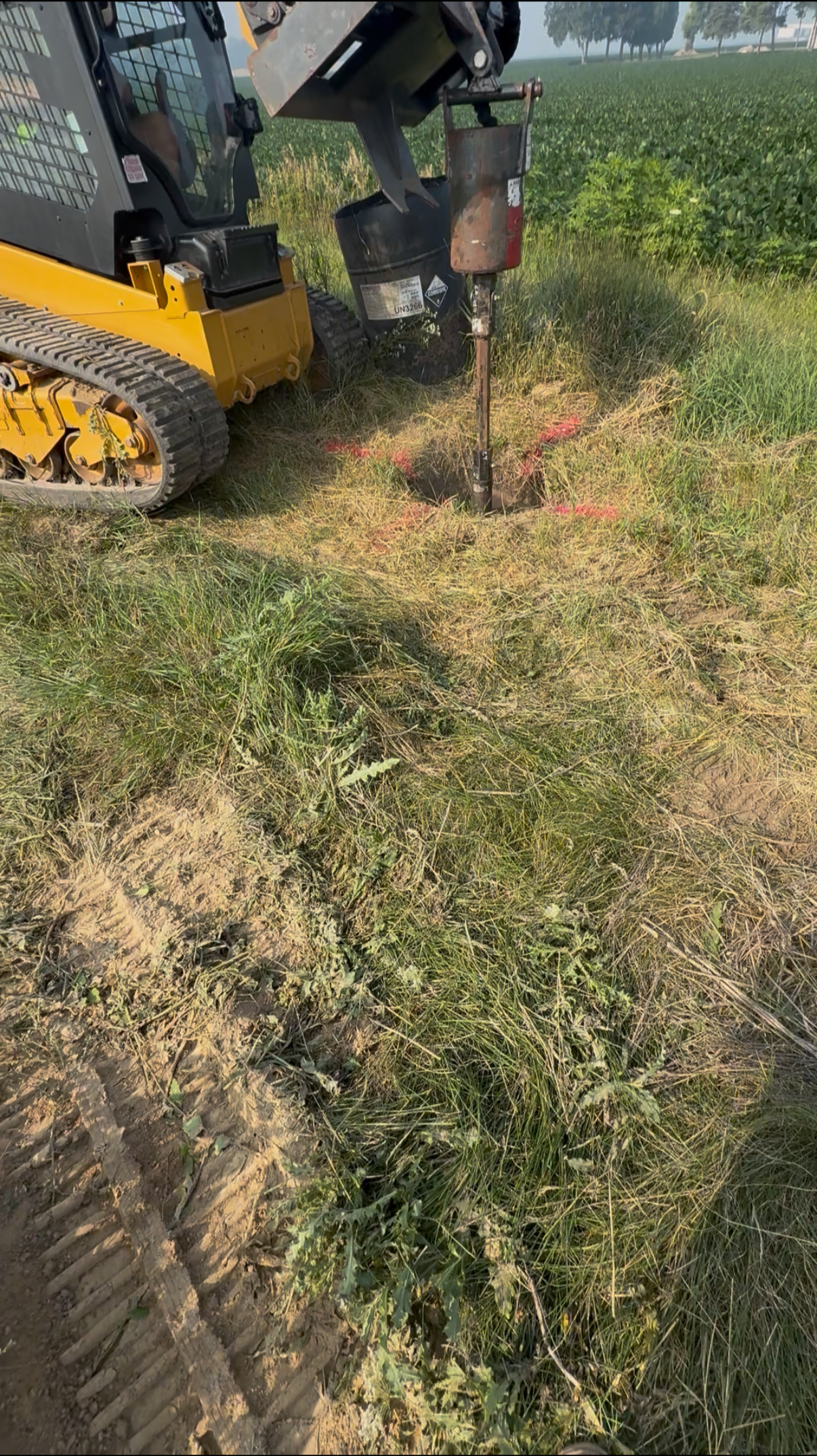 Auger drilling post holes for pole barn addition.