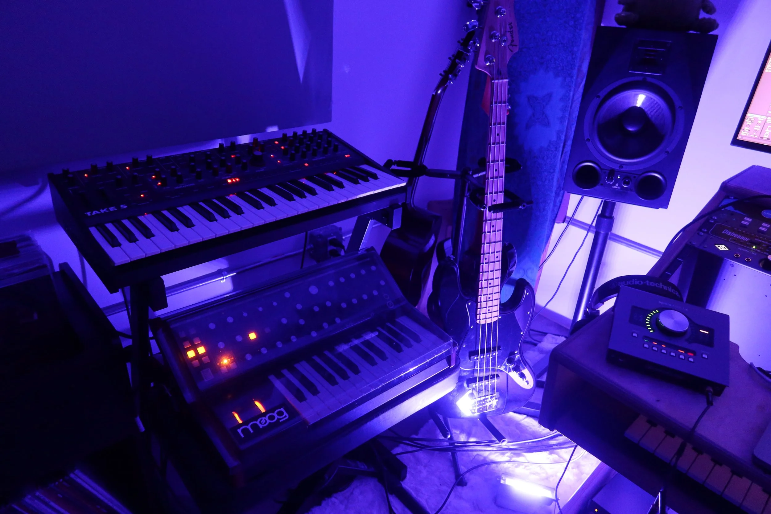 Synthesizers, bass guitar and studio monitor under blue lighting at BLNDMAN Records