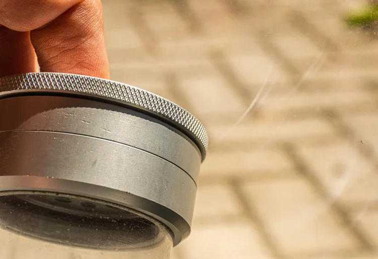 Hand lifting the textured aluminium lid of the grinder