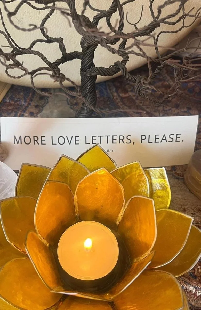 Lotus-shaped glass candle holder with tealight beside note requesting more love letters