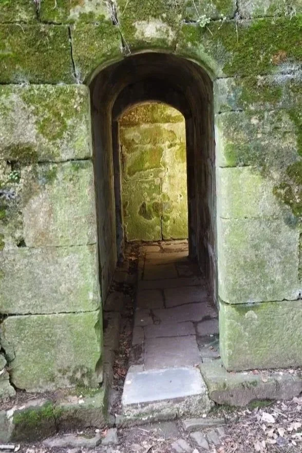 Atmospheric stone tunnel with moss-covered walls and portal-like entrance feeling