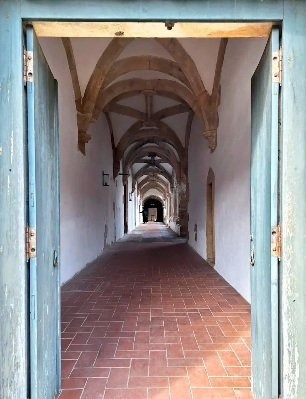 Historic hallway viewed through weathered turquoise wooden doorframe