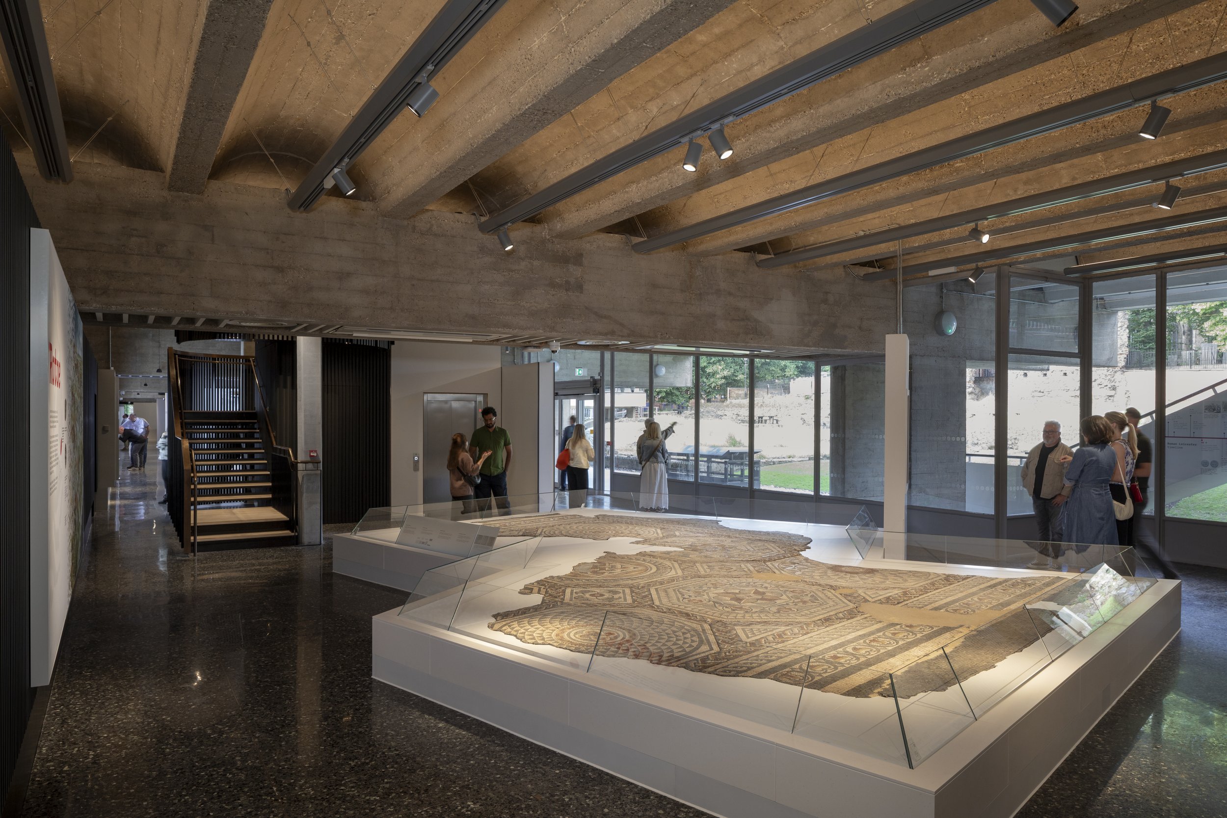 Levitate Architects — Museum interior with display cases showcasing ancient artifacts, large windows with natural light, and visitors observing exhibits.