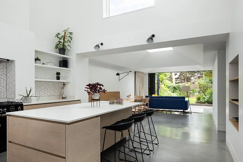 Levitate Architects Gloucester Drive contemporary kitchen extension featuring light oak cabinetry, white surfaces, and a double‑height ceiling opening to the garden.