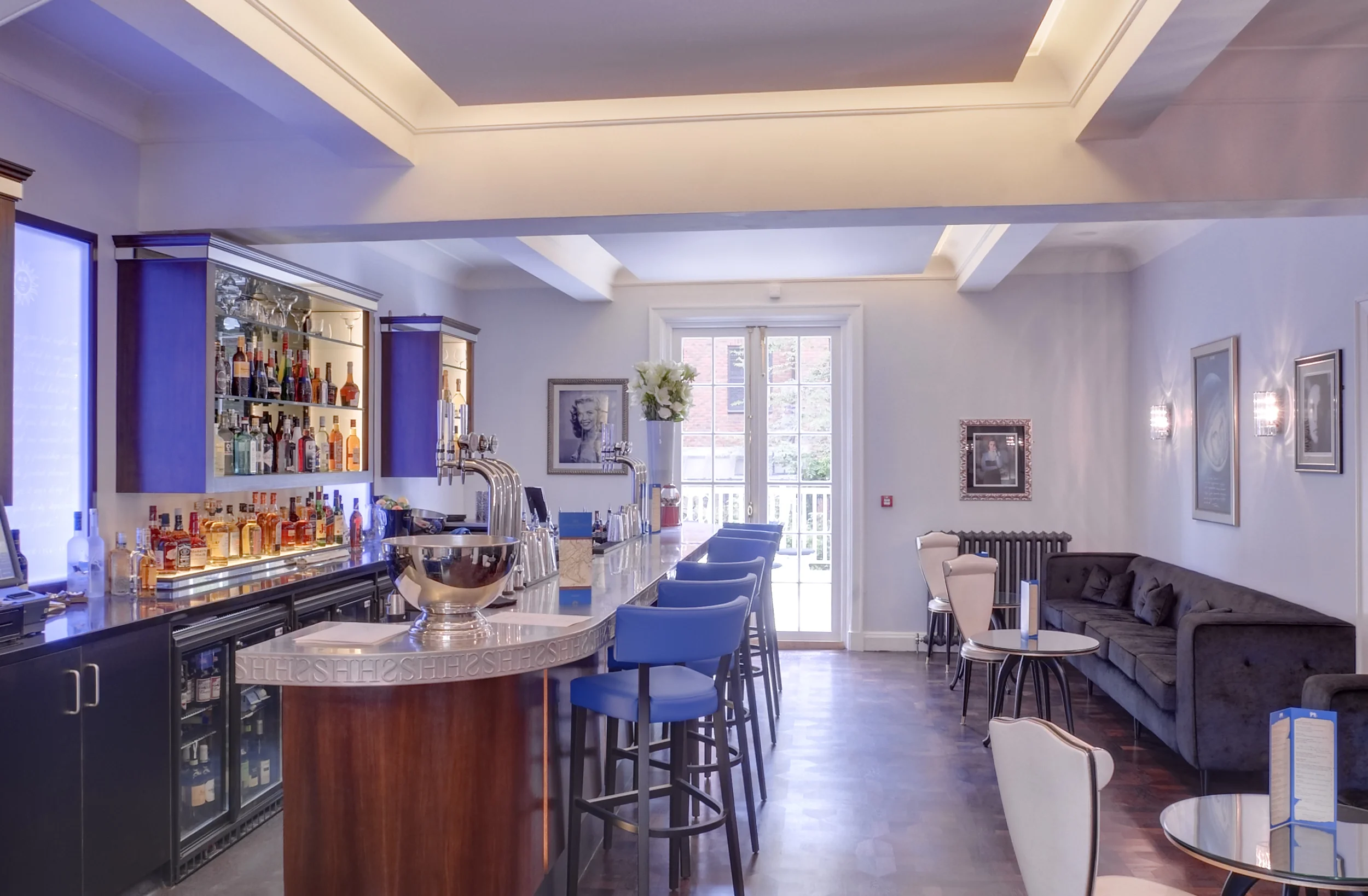Levitate's Southernhay Hotel bar with blue upholstered stools, backlit drinks display and views onto the garden terrace
