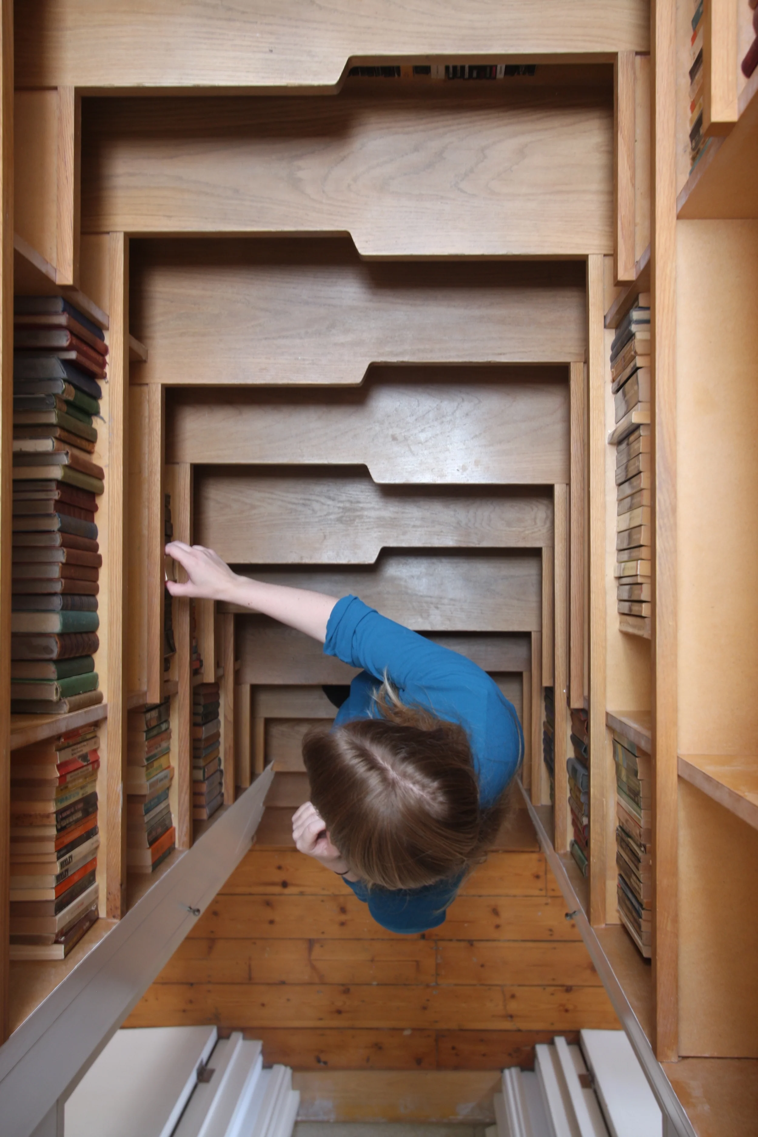 Levitate's Bookcase Staircase viewed from above, showing a person reaching into the book-lined stair structure