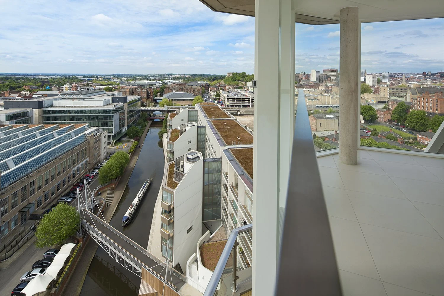 Elevated balcony view of the Nottingham One mixed-use regeneration scheme by Levitate Architects, showcasing green roofs, a canal bridge, and the urban skyline.