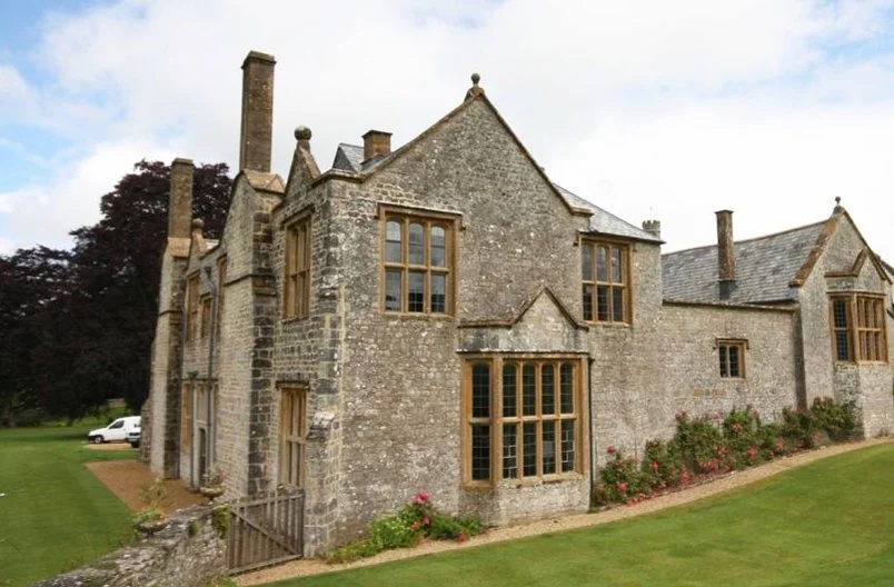 Levitate Architects' Whitestaunton House: A view lookingat the rear elevation toward the old timber-framed windows and stone masonry of the historic manor.