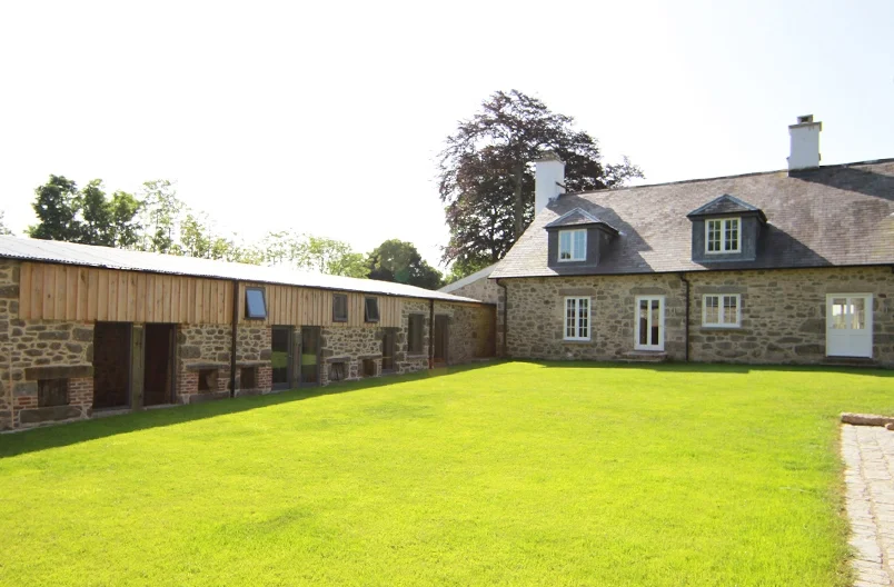 Levitate Architects Torhill Farm heritage restoration showing stone farmhouse and converted barns with timber detailing around a landscaped courtyard.