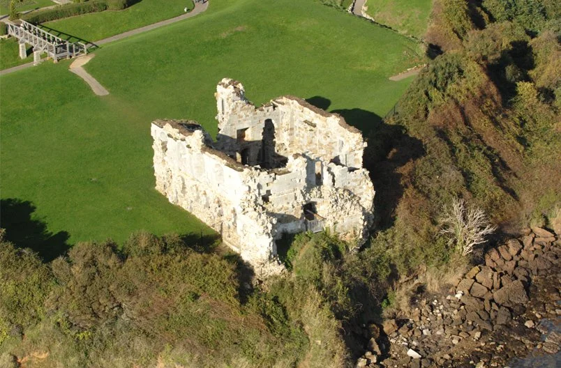 Award Winning Levitate Architects' Sandsfoot aerial view shows a ruined stone castle on a cliff, balancing heritage conservation & coast.