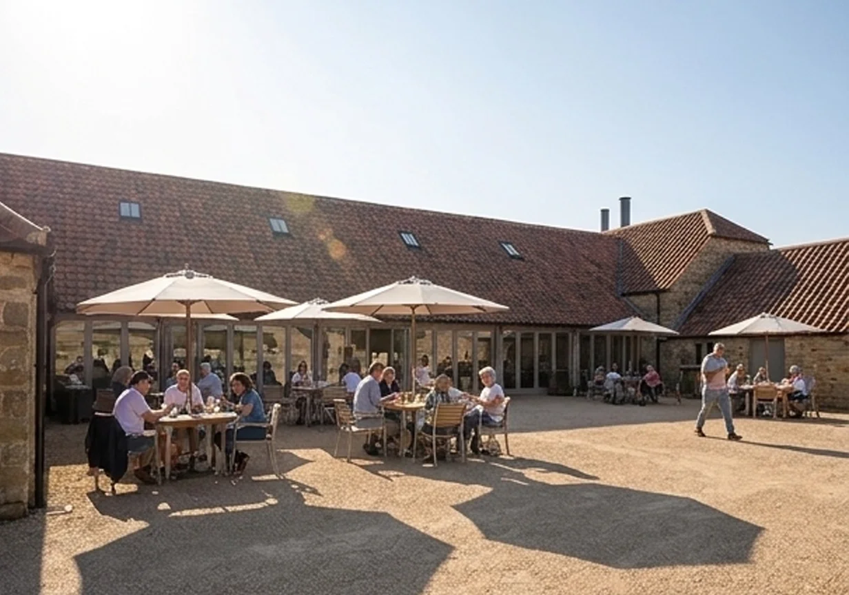 Levitate's Barrington Court sunlit courtyard cafe terrace with umbrellas and outdoor seating beside the tiled barns