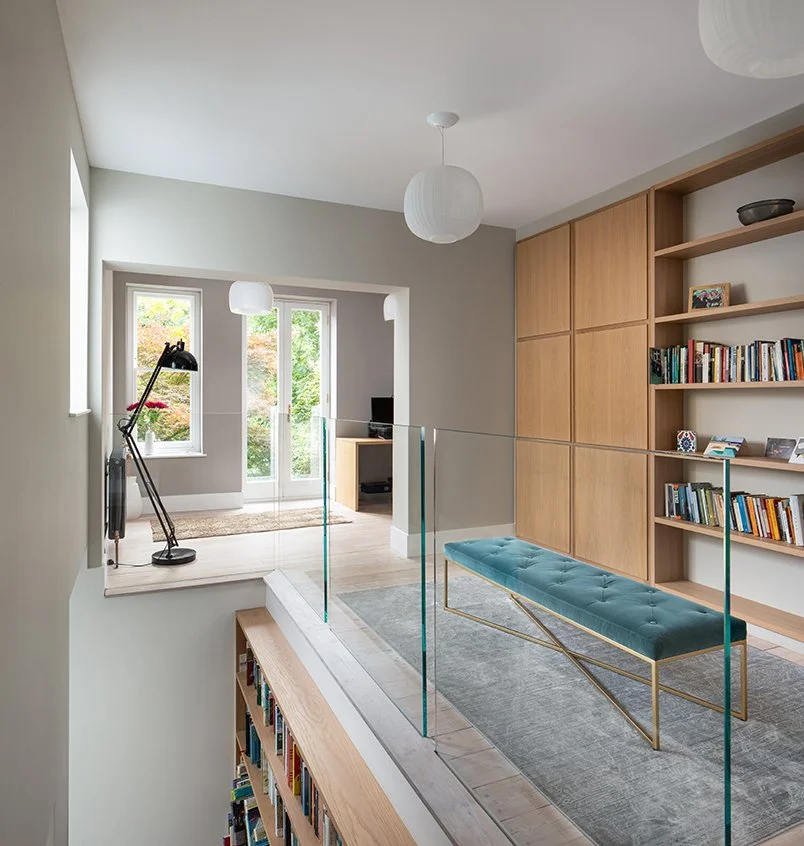 Levitate Architects Gloucester Drive contemporary interior extension with reading mezzanine, glass balustrade, and bespoke oak joinery.