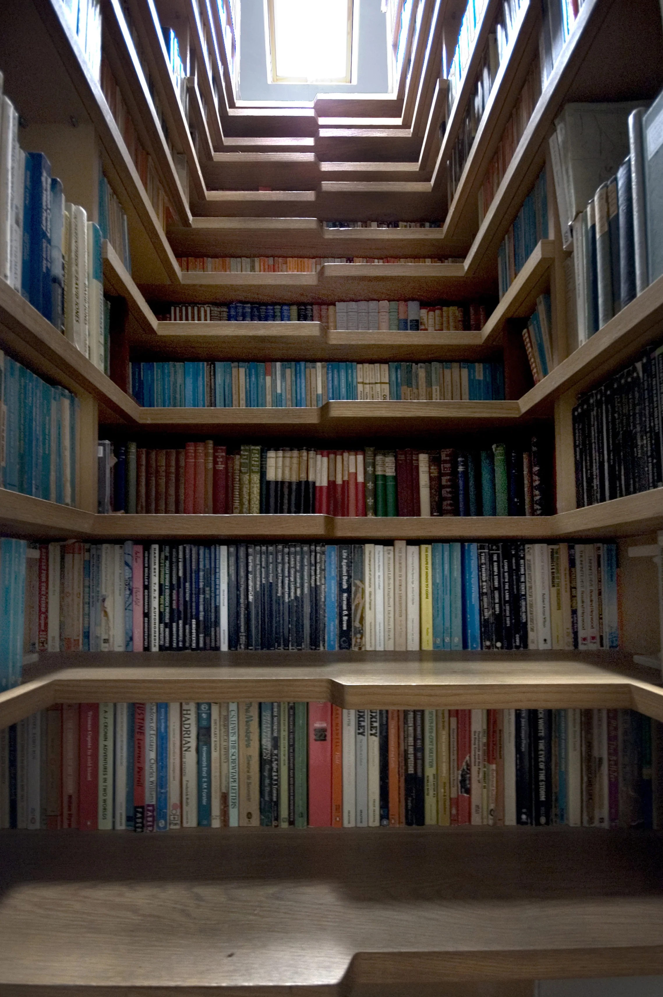 Levitate's Bookcase Staircase view looking up towards the skylight, illuminating the book-lined stair treads and shelves