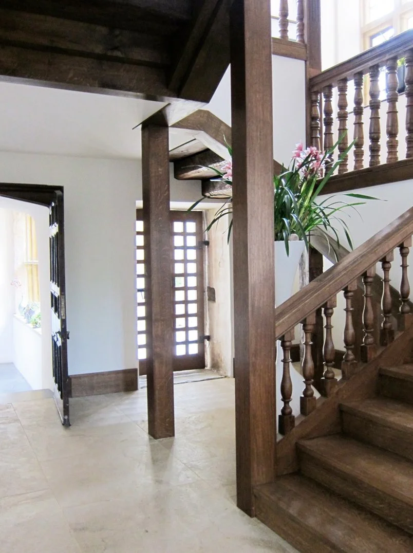Levitate Architects' Whitestaunton House: A contemporary cantilevered wooden staircase with clean lines, contrasting beautifully against the rustic texture of the historic stone interior walls.
