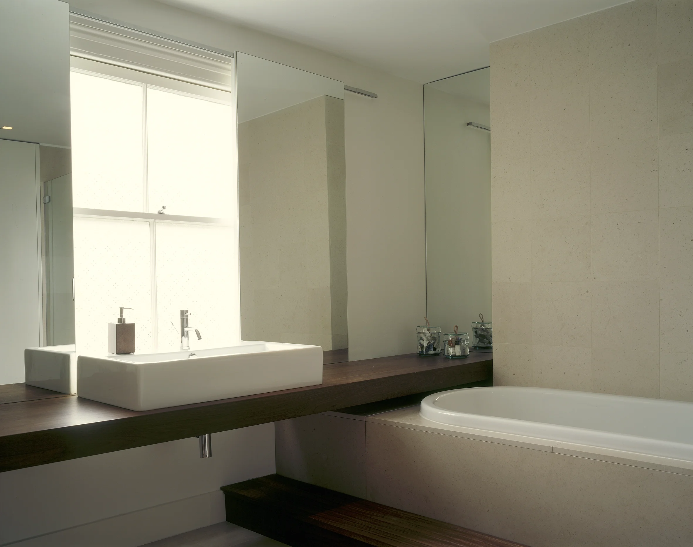 Levitate's wandsworth house a large frosted window floods this minimalist bathroom with soft, abundant natural light.