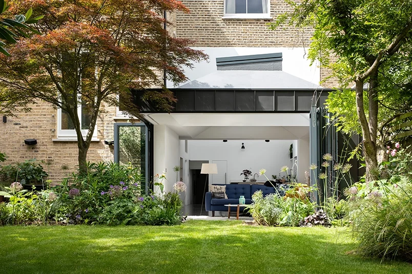 Levitate Architects Gloucester Drive modern home extension connecting living space to garden through full‑height glazed doors and minimalist interiors.
