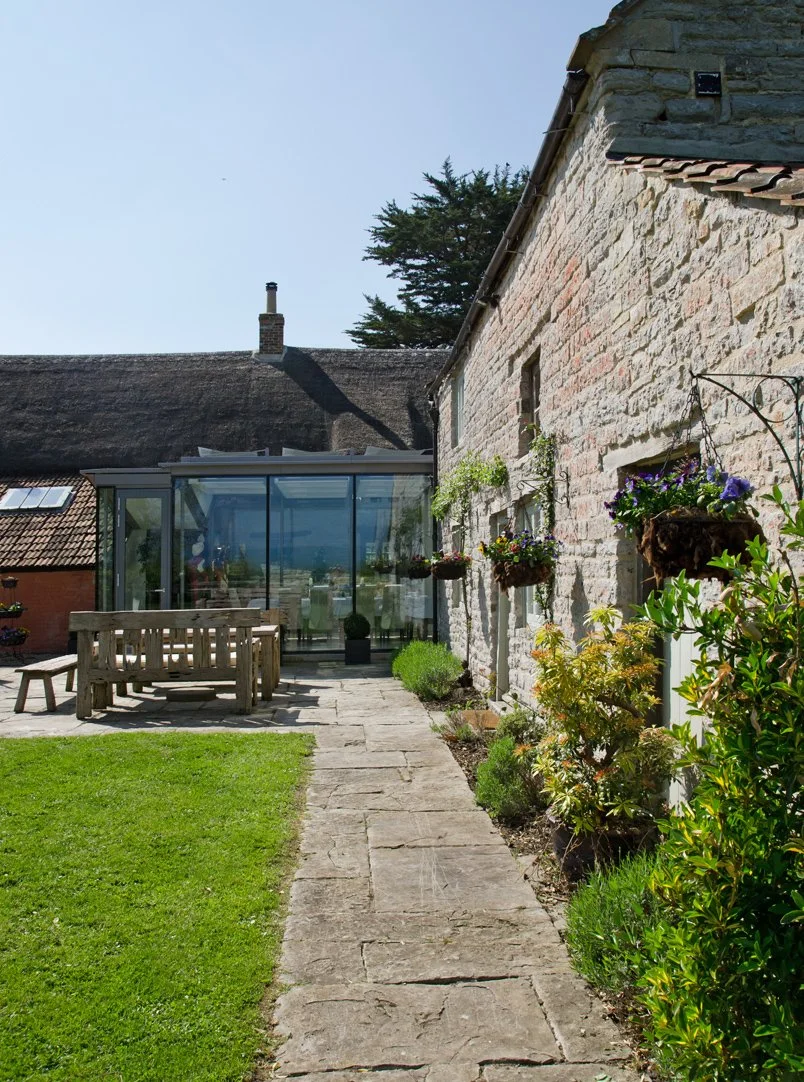 Award Winning Old Farm by Levitate Architects: Angled view down a stone walkway leading past restored stone wall toward the contemporary glass link.
