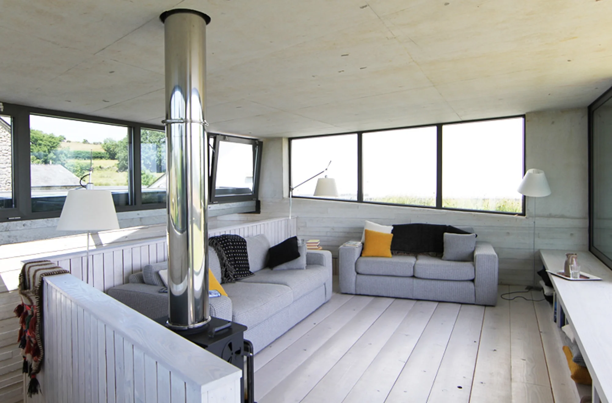 Levitate Architects Torhill Farm heritage living space featuring panoramic windows, wood‑burning stove, and views across Dartmoor farmland.