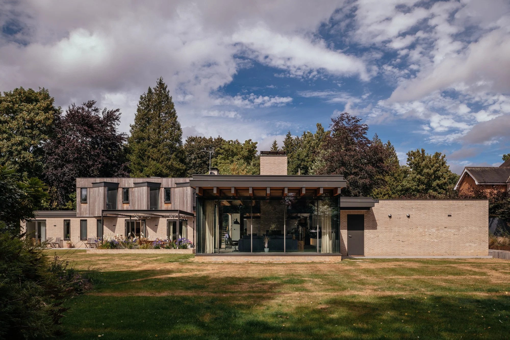Exterior view of a new mid-century inspired modern house designed by Levitate within a Conservation Area, subtle massing and carefully positioned windows form a bright and light home connected to its landscaped setting.