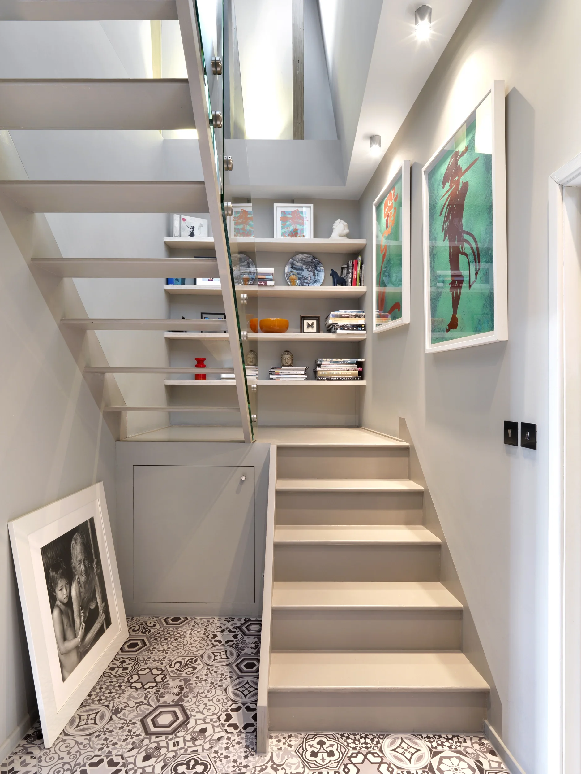 Levitate's Shoreditch Loft staircase with built-in shelving, patterned tiled floor and colourful framed artwork