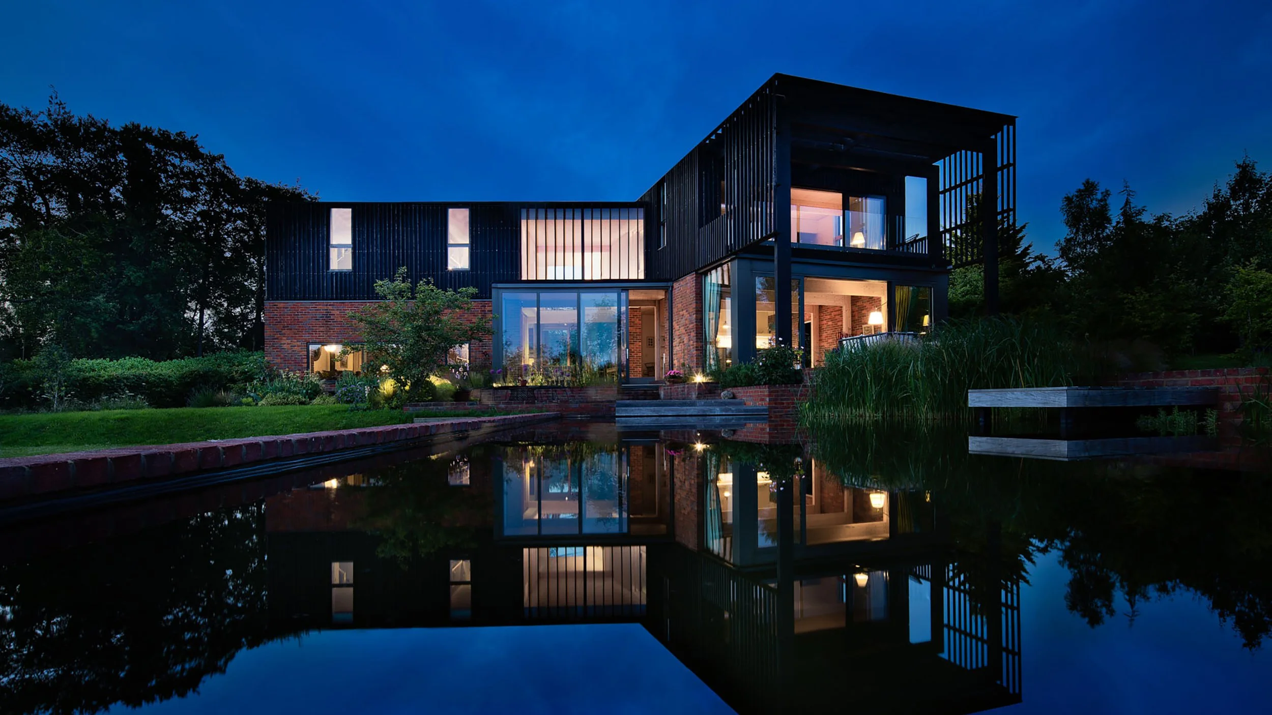 Award-winning PATCH house exterior by Levitate Architects, showing mid-century modern passive design integrated with a natural swimming pond and gardens.