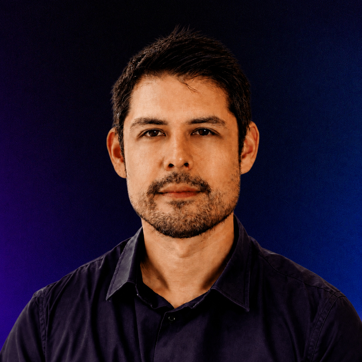 Alex Owens, A man with short dark hair, light skin, and a goatee, wearing a dark shirt, looking at the camera against a dark blue background.