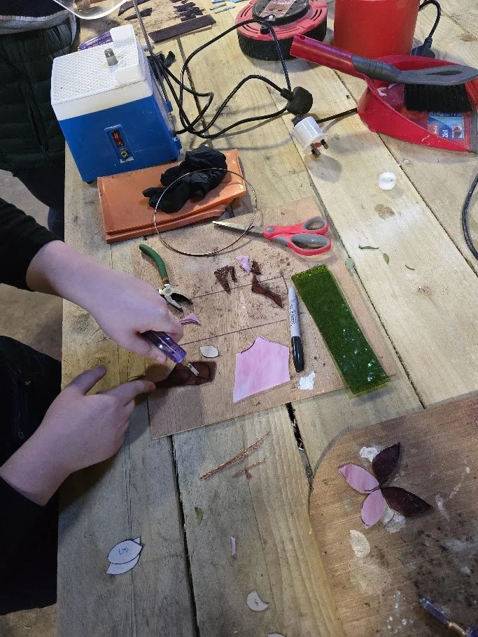 A student creating a piece of glass art at the rustic workbench