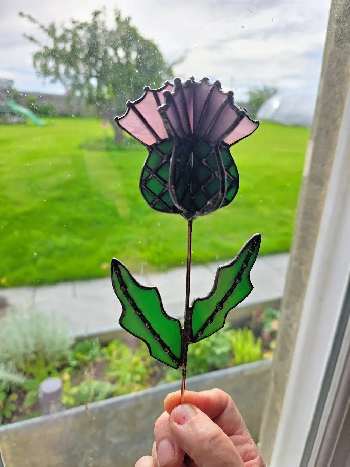 A 3d stained glass thistle with purple glass and green glass