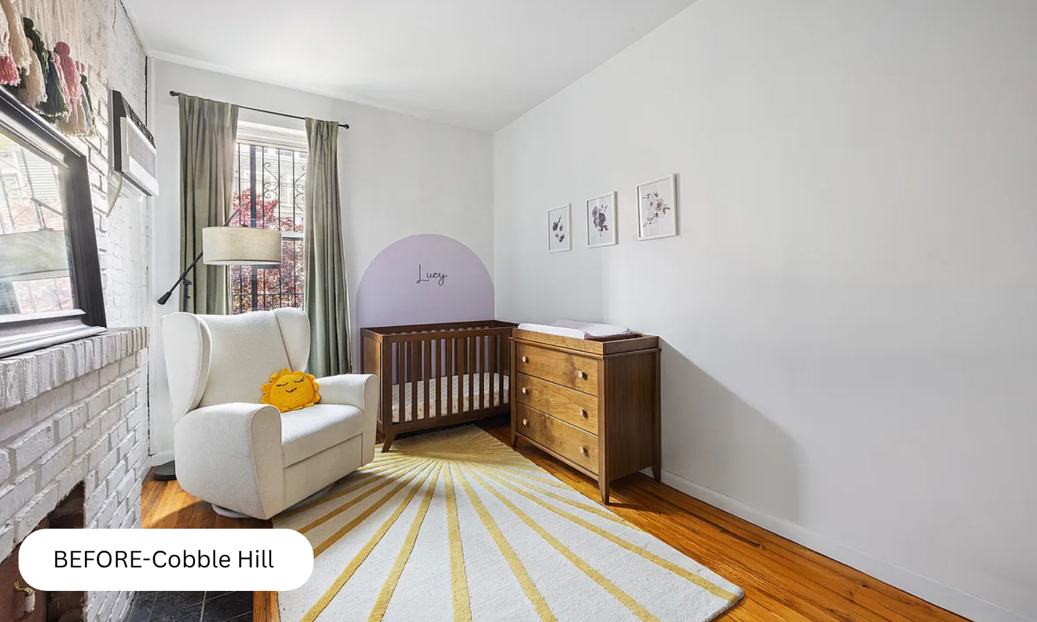 Nursery with white armchair, yellow sun pillow, crib, dresser, framed art, window with curtain, and a striped rug.
