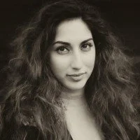 A woman with wavy, voluminous hair and a slight smile, looking at the camera.