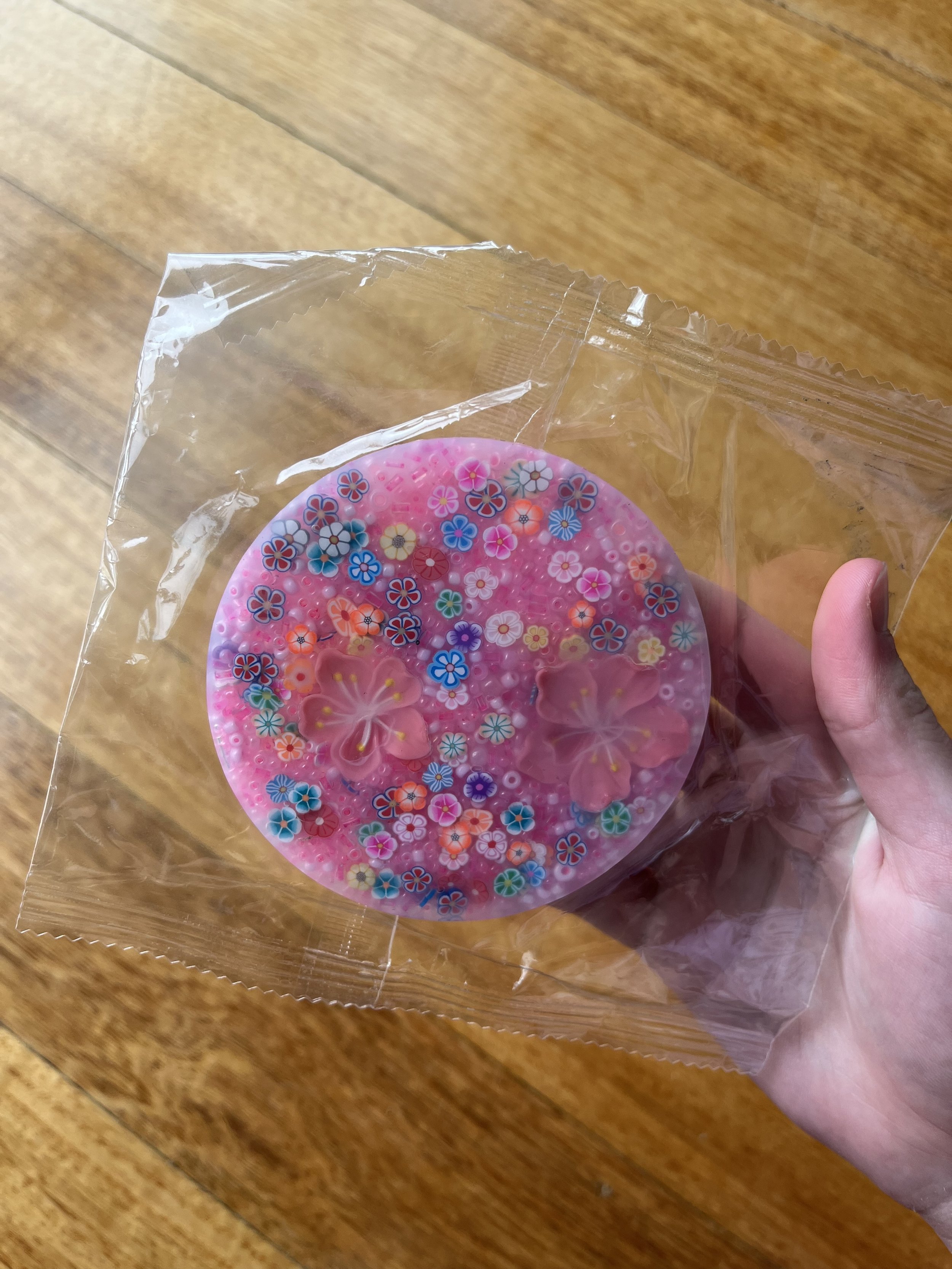 A person holding a pink picky pad decorated with colorful flower patterns.