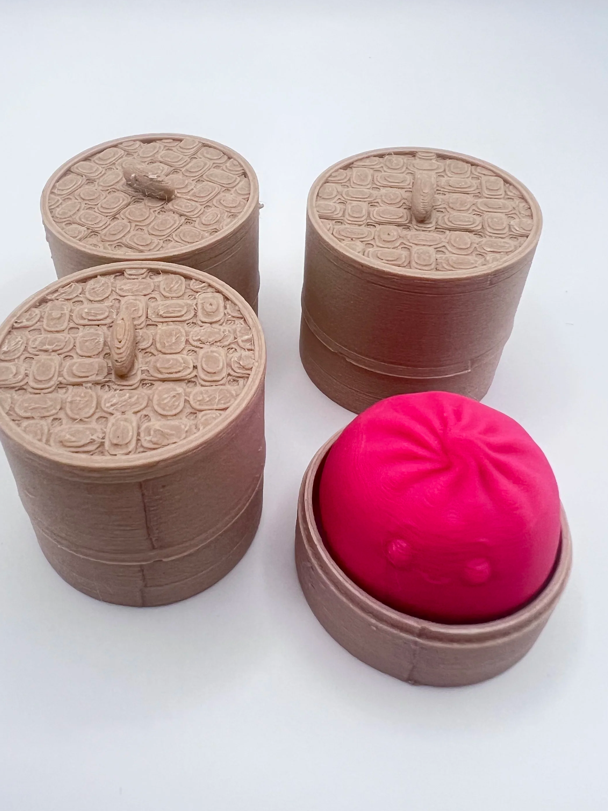 Set of dumpling clinkers, the pink one has its lid off.