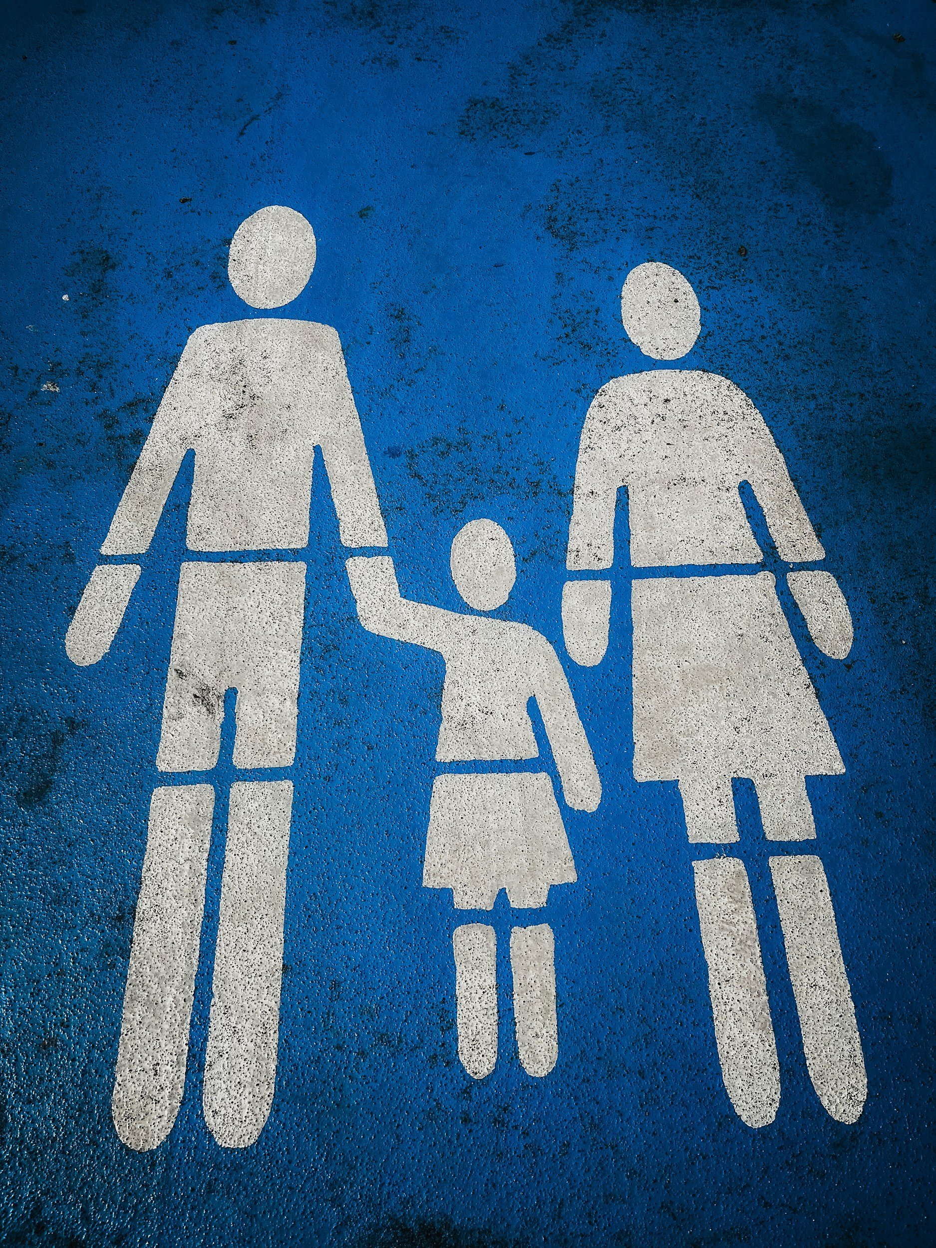 Blue pedestrian crossing lane for people with children, featuring white silhouettes of two adults and two children holding hands.