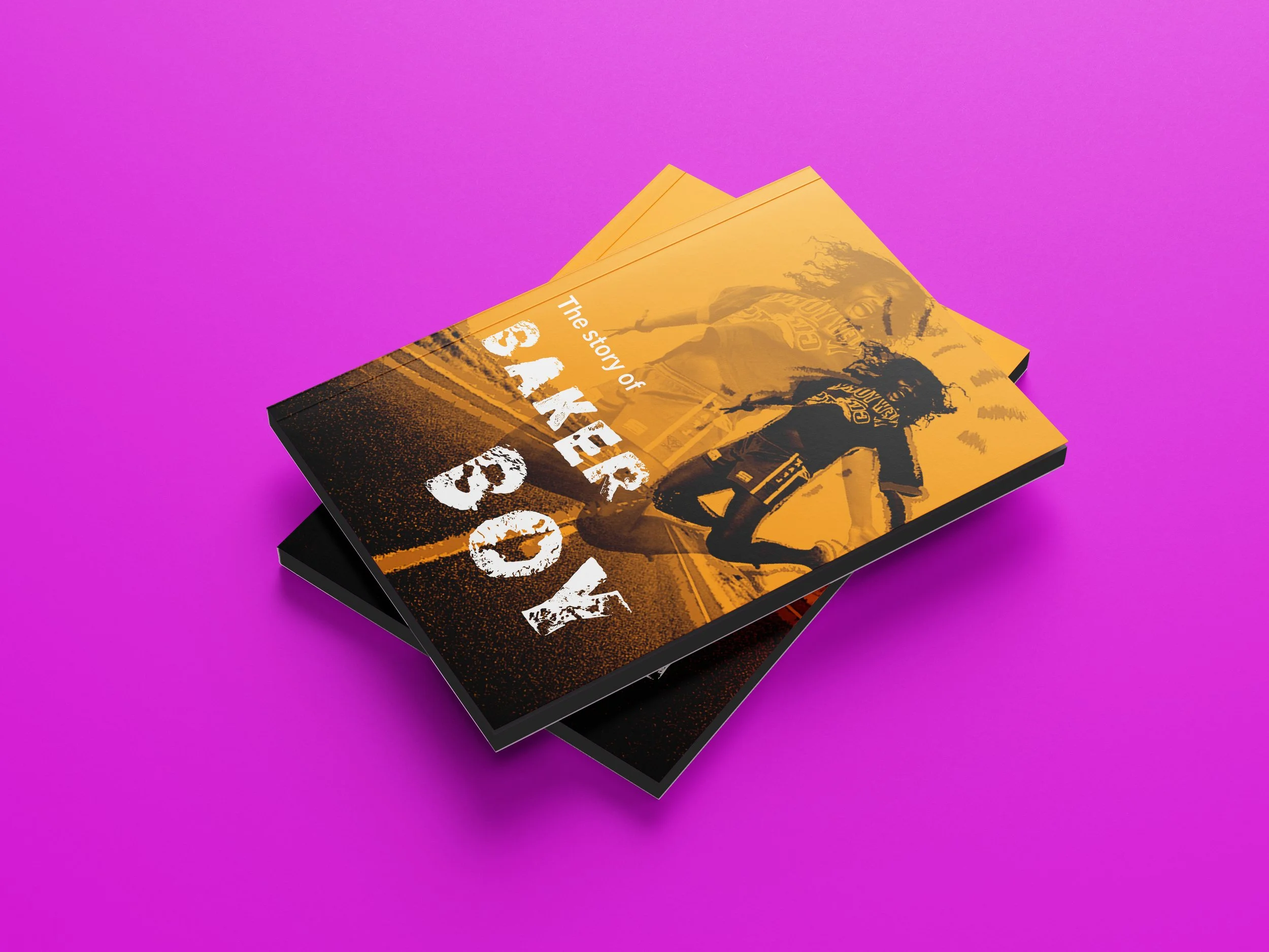 Stack of yellow and black brochures with a football player on the cover and the title 'The story of SARK'. The background is vibrant pink.