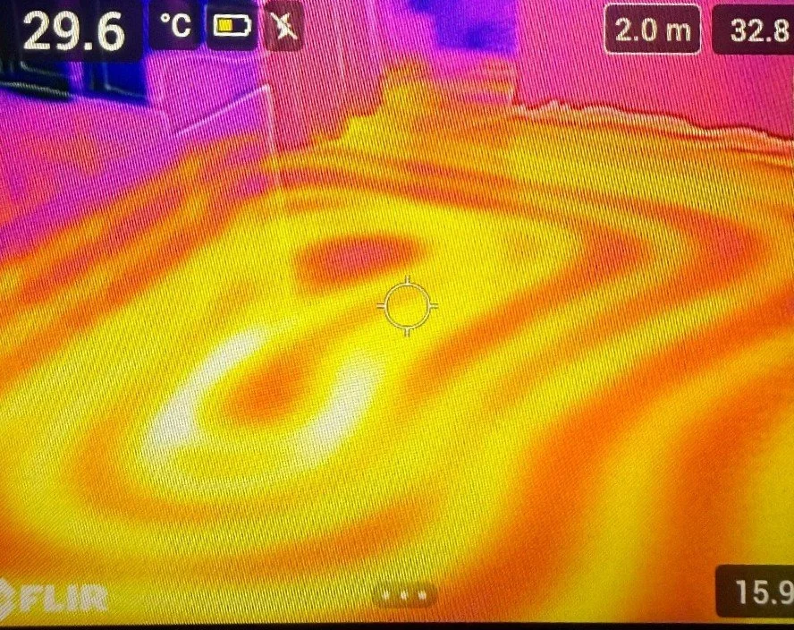 Thermografieaufnahme eines Bodens, mit farblichen Mustern, die Temperaturunterschiede anzeigen, in den Farben Gelb, Orange, Rot und Pink.