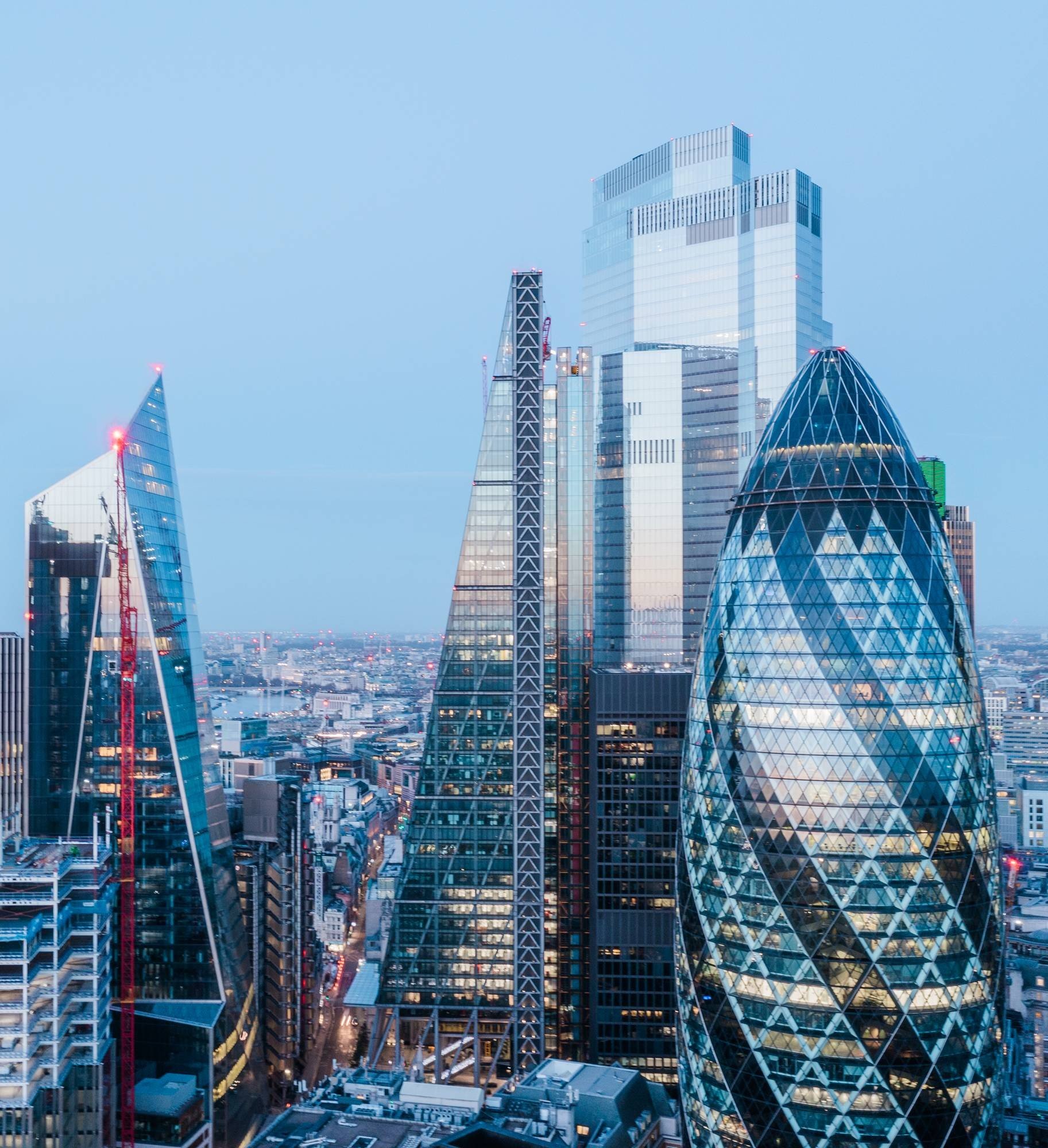 Skyline of London with modern skyscrapers, including the Gherkin and The Shard, during dusk.