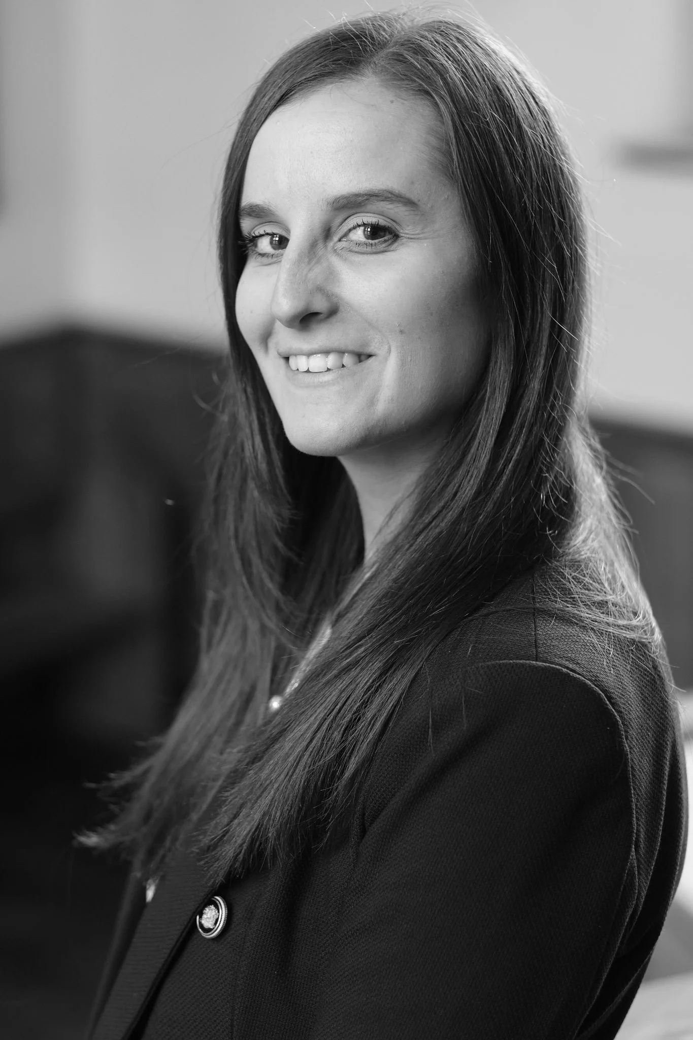 Black and white photo of a woman with long hair, smiling and looking towards the camera.