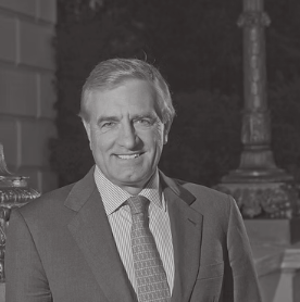 Black and white photo of a smiling man in a suit and tie.