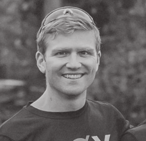 A smiling young man with short hair wearing a T-shirt outdoors.