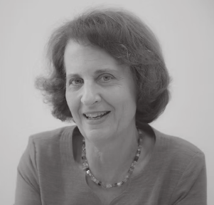 Black and white portrait of a woman with short, wavy hair wearing a top and necklace smiling at the camera.