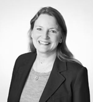 Black and white photo of a woman with shoulder-length hair, smiling, wearing a blazer over a top.
