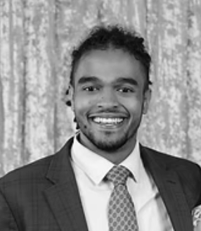A smiling man in a suit and tie with a patterned background